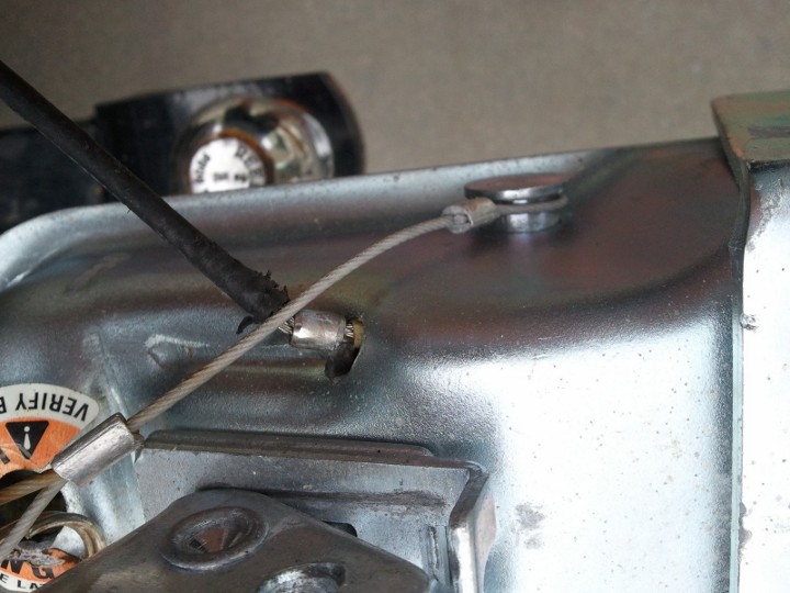 Close-up of a metal housing with a cable attached, showing a warning sticker