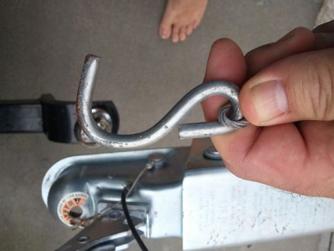 1994 Ford Bronco - A close-up shows a hand holding a trailer coupler hook, with the safety chain attached.