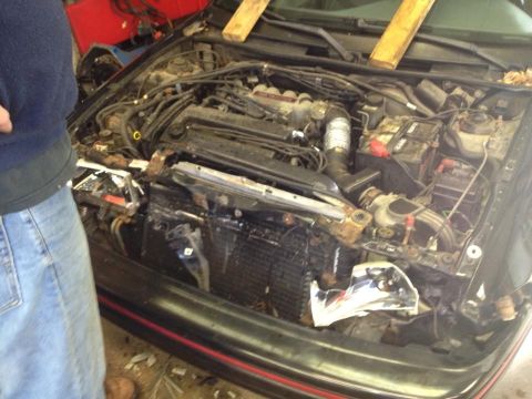 1988 Ford Bronco - The engine bay shows a damaged radiator and various engine parts, with a person standing to the left.