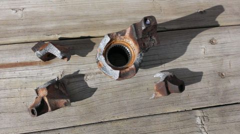 1994 Ford Bronco - Damaged differential housing and its broken fragments are displayed on a wooden surface.