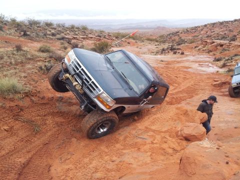 1994 Ford Bronco - A Ford Bronco is stuck on a steep, muddy incline during an off-road excursion.