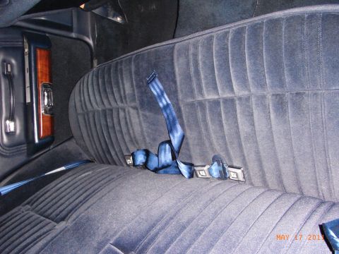 1991 Ford Crown Victoria LTD - The interior of a vehicle shows a blue velvet bench seat with seatbelts.