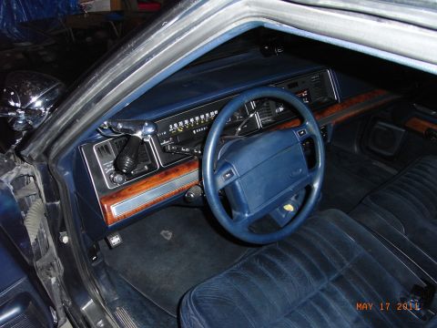 1991 Ford LTD Crown Victoria - The interior of a 1991 Ford Crown Victoria LTD is shown, plush blue velour seats and wood-grain trim.