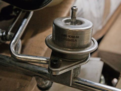 1990 Ford Bronco - A close-up view of a fuel pressure regulator, showing stamped part numbers.