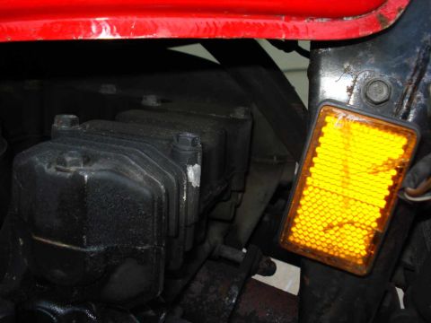 2008 Ford Crown Victoria - Close-up of engine components and a yellow reflector, with red paint visible at the top.