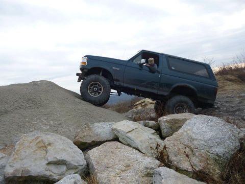 1995 Ford Bronco - A 1995 Ford Bronco navigates a challenging rocky terrain, demonstrating its off-road capabilities.