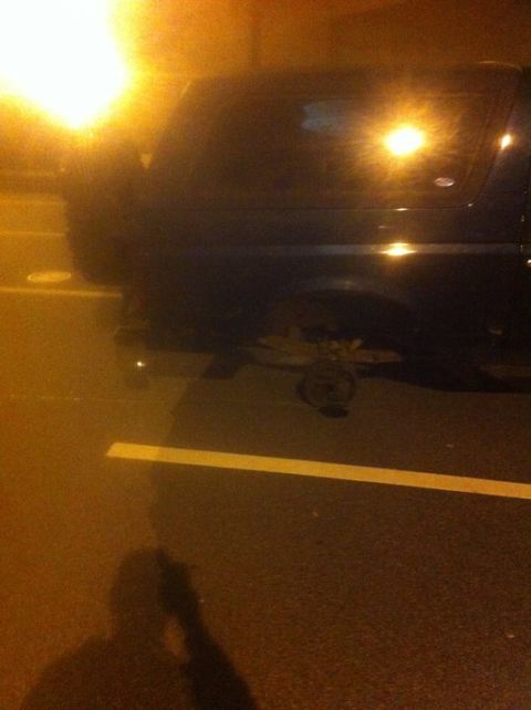 1995 Ford Bronco - A dark SUV is seen with a missing rear wheel, parked on asphalt at night.