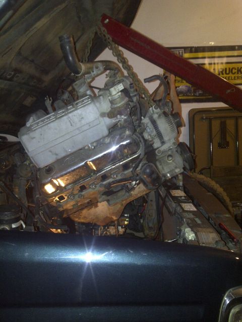 1995 Ford Bronco - Engine removal in progress, with a red engine hoist lifting the V8 engine out of the vehicle.