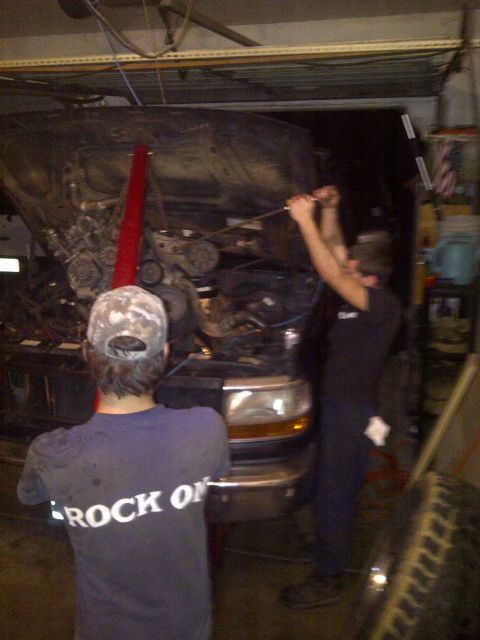1995 Ford Bronco - Mechanics are working on the engine of a 1995 Ford Bronco in a garage.