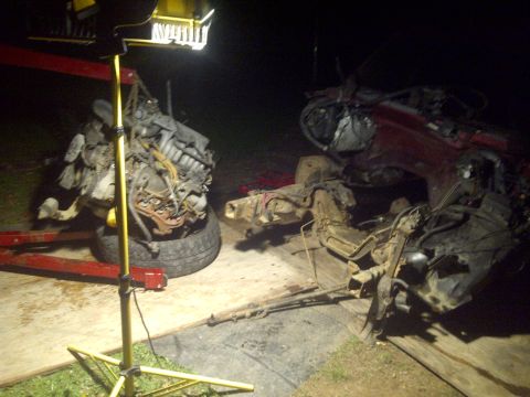 1995 Ford Bronco - Disassembled vehicle components are laid out on the ground at night.
