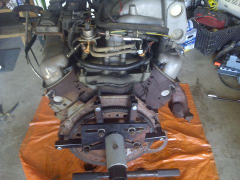 1995 Ford Bronco - Engine assembly on an orange tarp, showing fuel lines, wiring, and exhaust components.