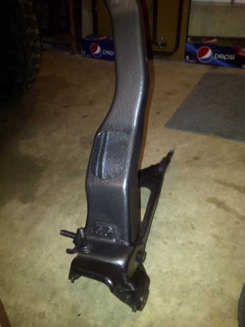 1995 Ford Bronco - A black metal automotive suspension part, possibly from a Ford vehicle, is shown in a garage setting.