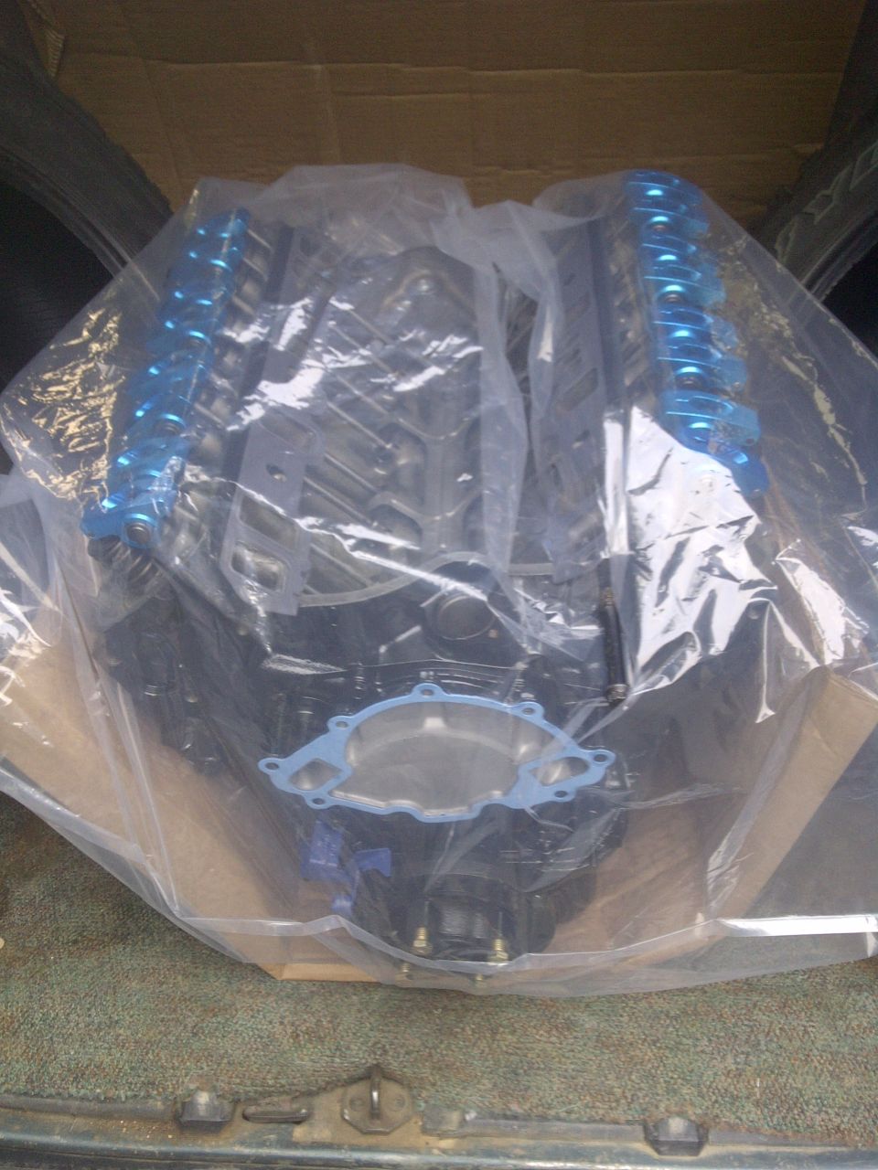 Engine covered in plastic wrap, with blue valve covers visible