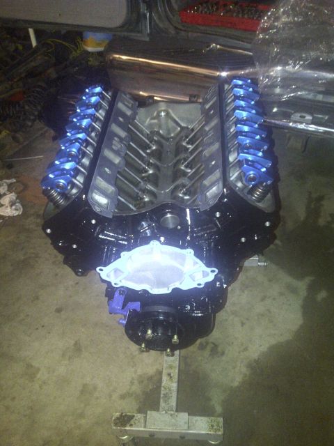 1995 Ford Bronco - A V8 engine with bright blue valve covers is mounted on a stand, ready for installation.
