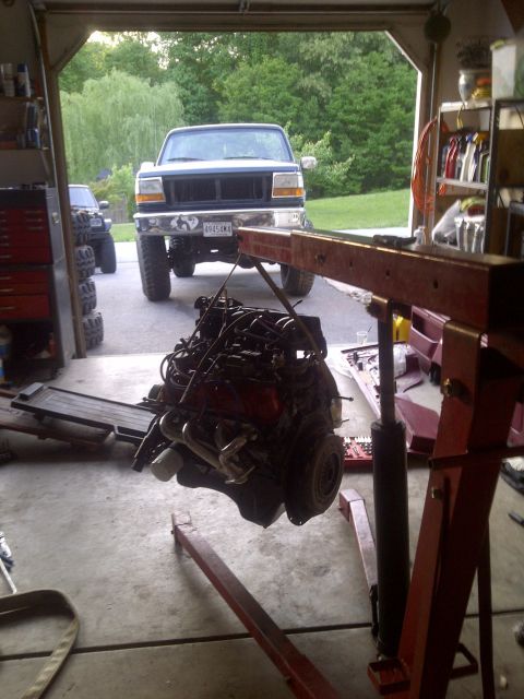 1995 Ford Bronco - Engine hoist lifting out the engine of a 1995 Ford Bronco in a garage.