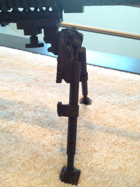 2013 Ford Mustang - A gun bipod is shown in detail, with its legs extended on a textured surface.