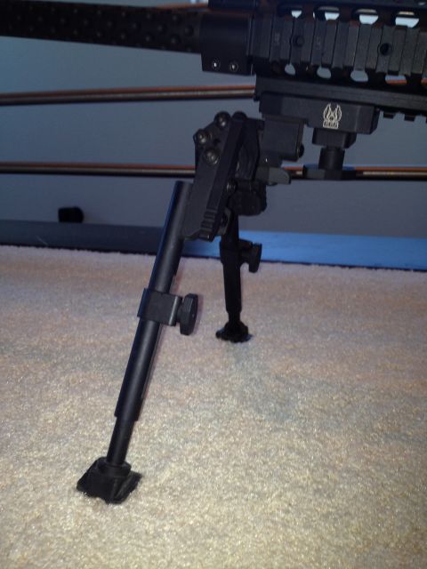 2013 Ford Mustang - A close-up view of a gun bipod attached to a firearm, resting on a carpeted floor.