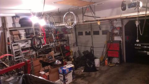 1995 Ford Bronco - A cluttered garage scene with storage shelves, tools, and bicycles, with a vehicle in the background.