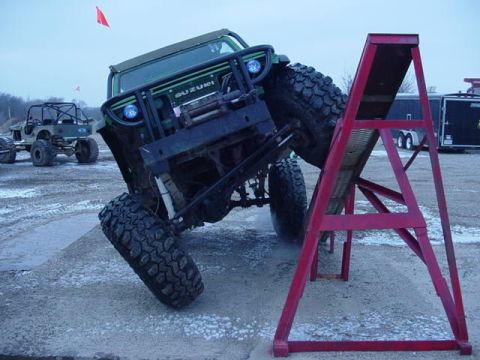 1992 Ford Bronco - A Suzuki Samurai is shown attempting an obstacle on a ramp during an off-road event.