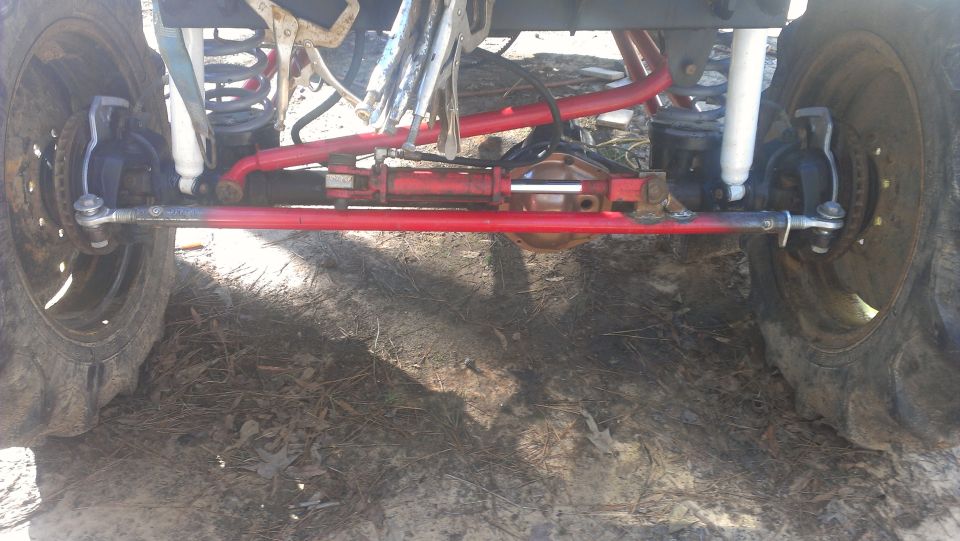 Red steering linkage and suspension components on a vehicle with large tires