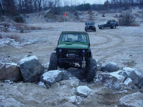 1992 Ford Bronco - A green off-road vehicle maneuvers through a rocky course with other SUVs visible in the distance.