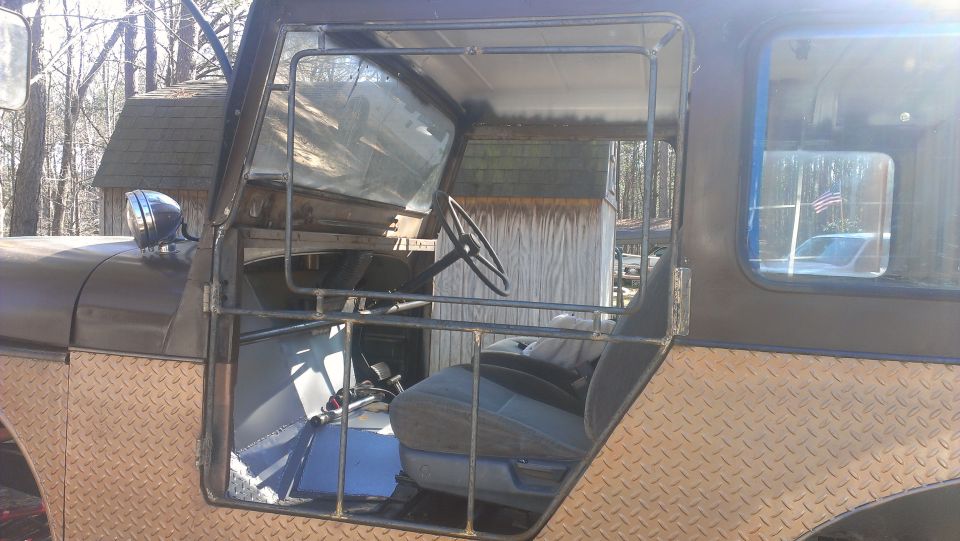 side view of a modified off-road vehicle's interior, showing seats, steering wheel, and roll cage