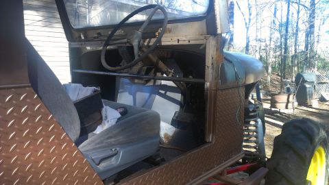 1978 Ford Bronco - The interior of a heavily modified and rusted off-road vehicle is visible, a large steering wheel and diamond plate accents.