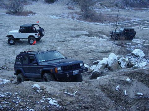 1992 Ford Bronco - Multiple off-road vehicles traverse a challenging, snow-dusted landscape.