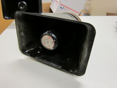 2001 Ford Crown Victoria - Close-up of a black siren speaker, a circular label with red and white markings.