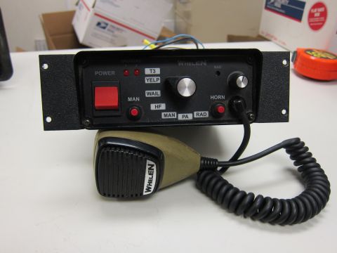 2001 Ford Crown Victoria - A Whelen siren control unit and microphone are shown on a white surface, cluttered surface.
