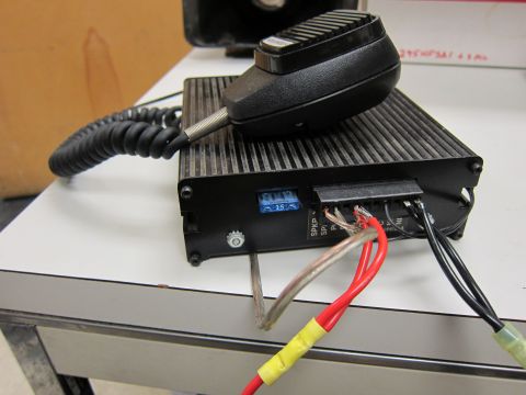 2001 Ford Crown Victoria - A siren amplifier and microphone are shown, with visible wiring and a fuse. The device is black with a ribbed top surface.