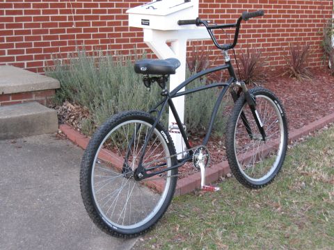 1994 Ford Bronco - A black cruiser bicycle with wide tires and BMX-style handlebars is parked outdoors next to a white mailbox.