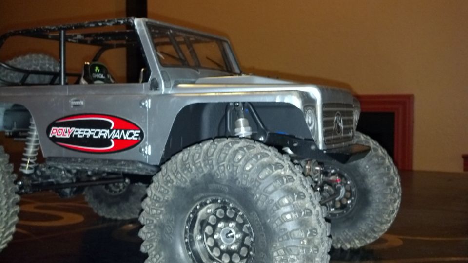 Silver RC rock crawler with large tires and 'POLYPERFORMANCE' decal on the door
