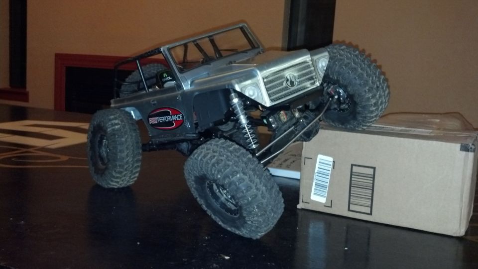 Silver RC rock crawler truck with large tires, "High Performance" decal