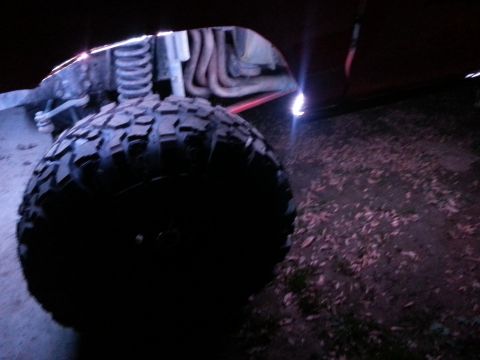 1978 Ford Bronco - Undercarriage view of a vehicle's wheel well and suspension system, illuminated by external lights.