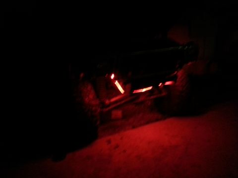 1978 Ford Bronco - Red underbody rock lights illuminate the ground beneath a vehicle in this nighttime photo.