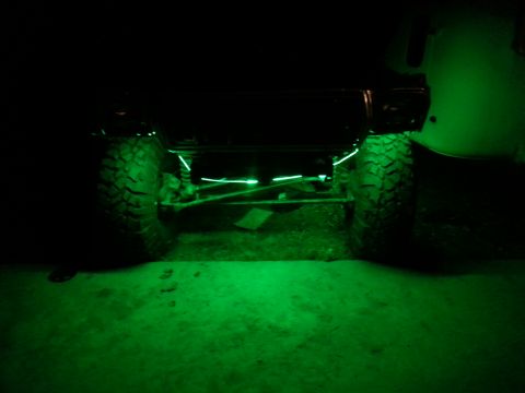 1978 Ford Bronco - Green underglow lights illuminate the suspension and tires of an off-road vehicle at night.