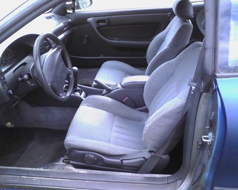 1991 Toyota Celica - The interior of a blue car shows grey fabric seats and the dashboard, with the driver's side door ajar.