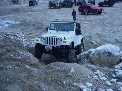 1992 Ford Bronco - Several off-road vehicles are seen on a rocky, outdoor course, with a white Jeep Wrangler in the foreground.