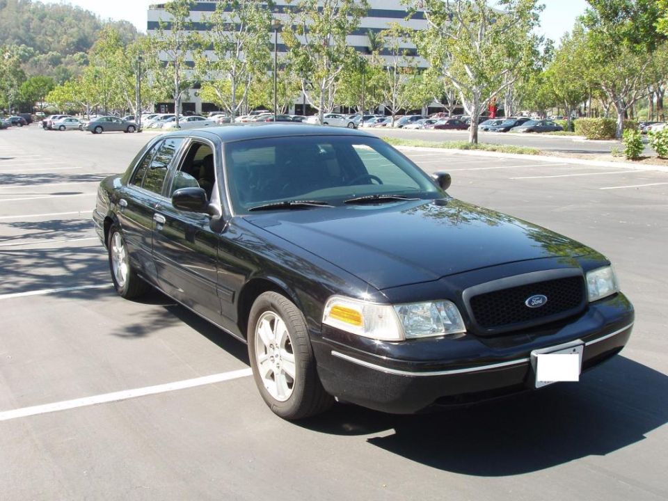 Black 2003 Ford Crown Victoria sedan parked in a lot, front 3/4 view, showing chrome trim and black grille