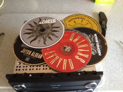 2008 Ford F-150 - A collection of CDs, artists like Jason Aldean, Lynyrd Skynyrd, and Nickelback, rests on top of a car stereo unit.