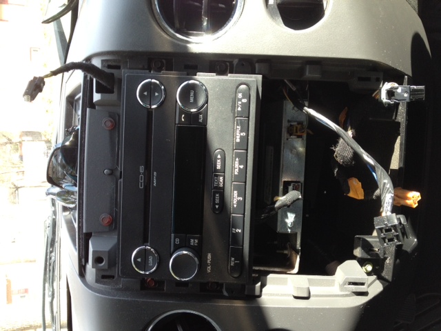 Car stereo and wiring removed from dashboard, showing exposed components