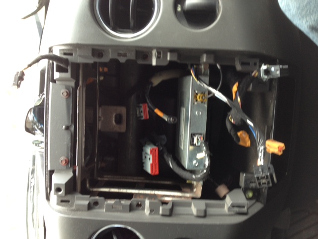 Vehicle center console disassembled with radio head unit cavity open and wiring exposed