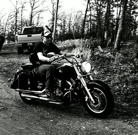 1995 Ford F-150 - A man rides a motorcycle down a dirt path, with a pickup truck visible in the background.