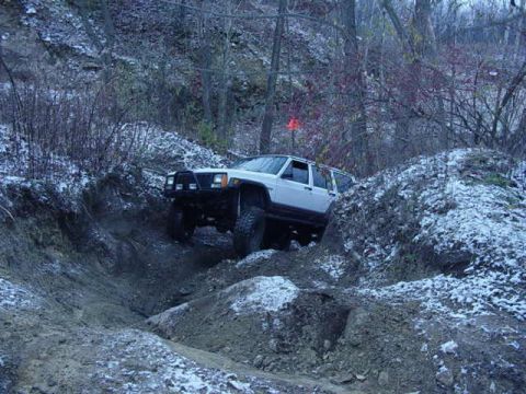 1992 Ford Bronco - White Jeep Cherokee navigating a challenging off-road trail with snow on the ground.