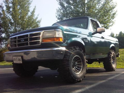 1995 Ford Bronco - This green Ford Bronco has a lifted suspension and aggressive off-road tires, suggesting it's built for more than just pavement.