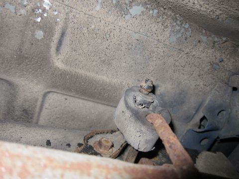 1991 Ford LTD Crown Victoria - Undercarriage view of a corroded exhaust hanger mount, showing signs of wear and rust.