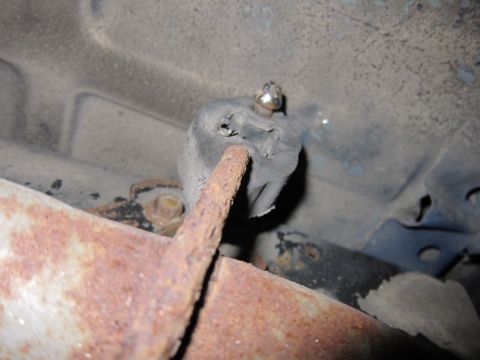 1991 Ford LTD Crown Victoria - Close-up of a worn rubber exhaust hanger mount attached to a rusted metal pipe.