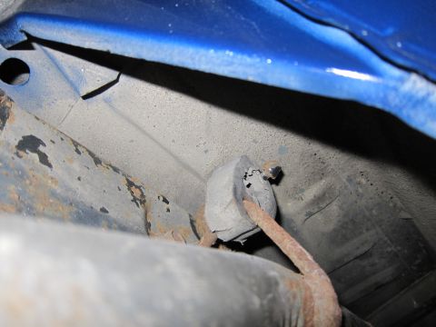 1991 Ford LTD Crown Victoria - Close-up view of a rusted exhaust hanger on the underside of a blue vehicle.