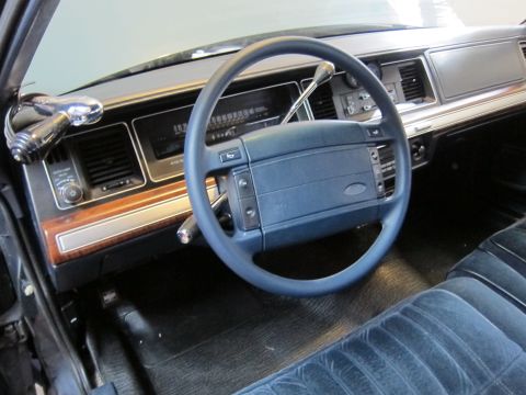1991 Ford LTD Crown Victoria - The interior of a 1991 Ford Crown Victoria LTD, blue velour seats, wood grain trim, and a column shifter.